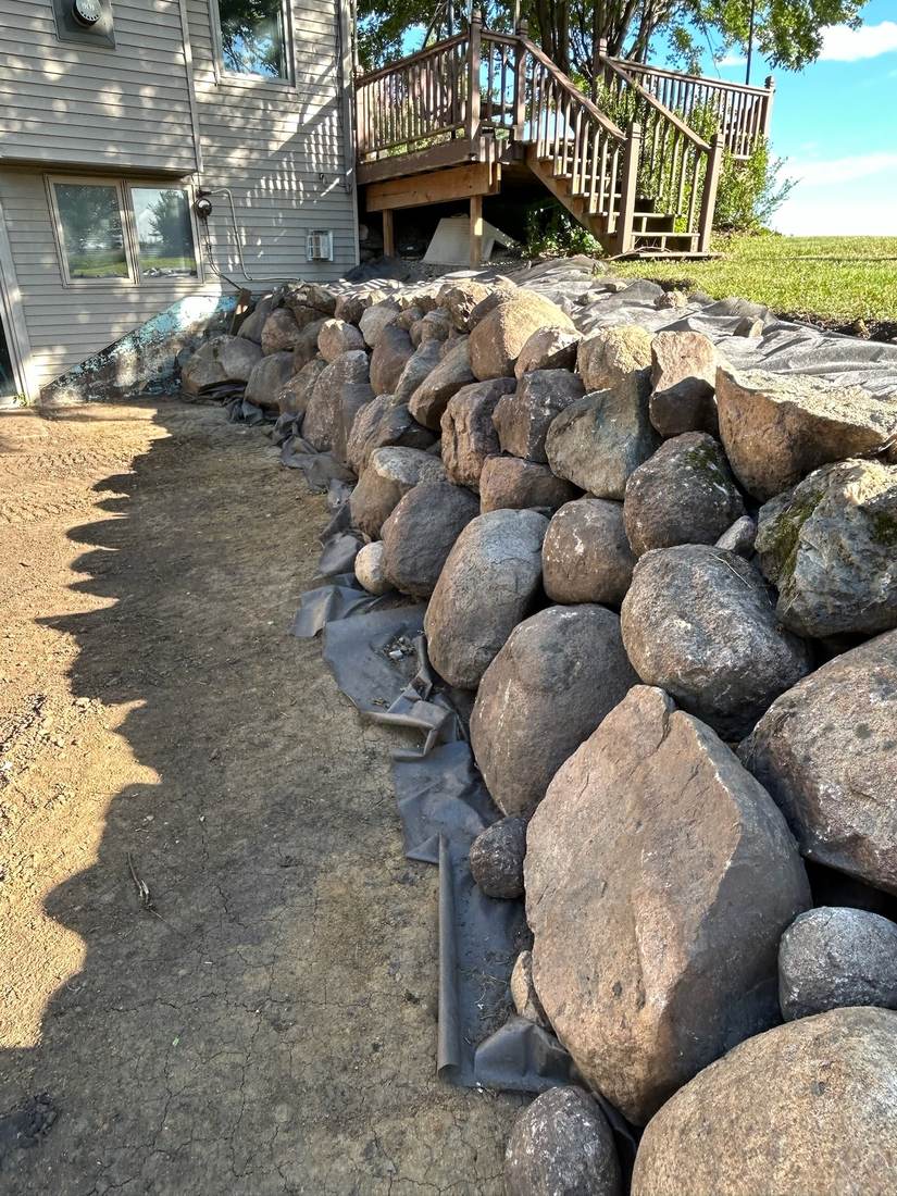 Finished boulder retaining wall along a walkway
