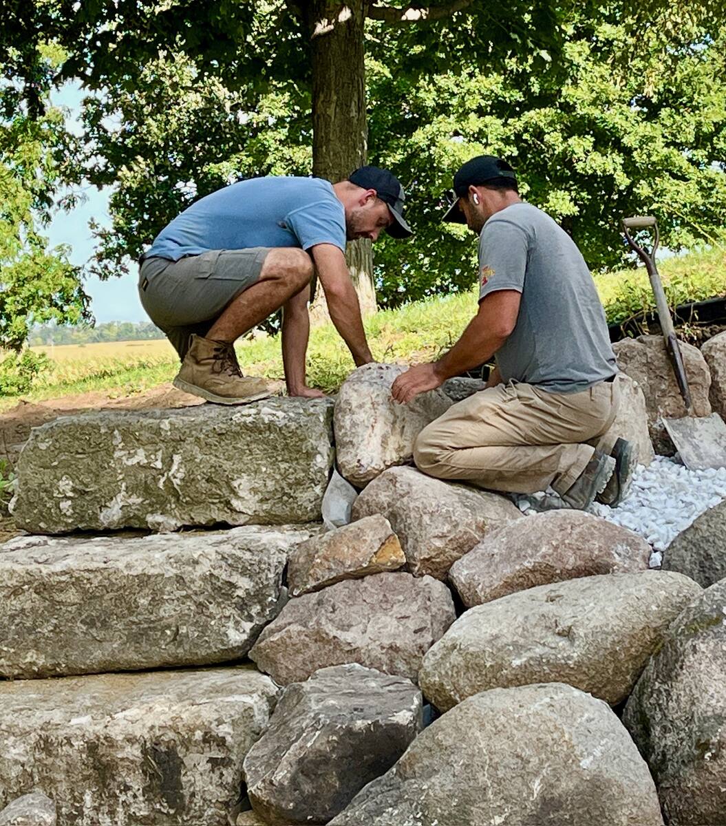 The Herbst brothers fitting a boulder into place on a retaining wall