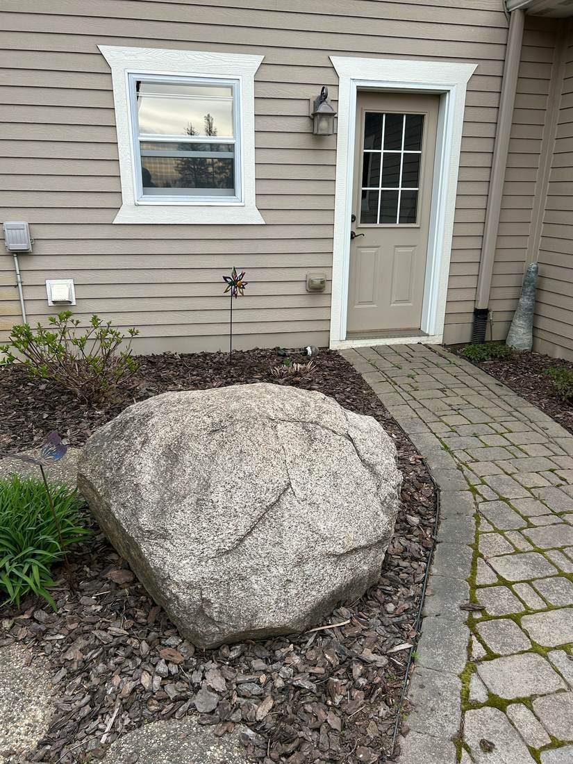 Approximately 5 foot boulder set beside a front walkway