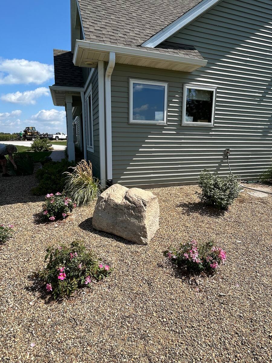 Centerpiece boulder set in a fresh landscaping bed at a home's corner