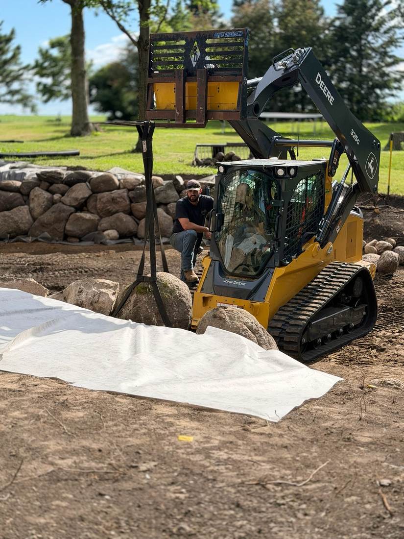 Crew member working alongside equipment on a boulder wall job