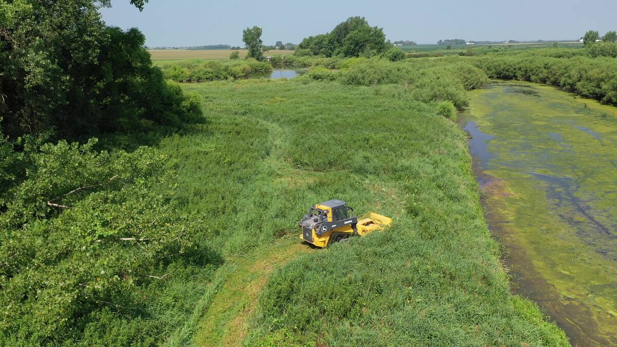 Aerial view of a forestry mulcher clearing a trail along a creek edge on a hunting property
